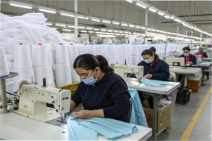 Workers sewing garments in large textile factory