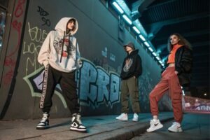 Three models wearing trendy streetwear posing in urban setting
