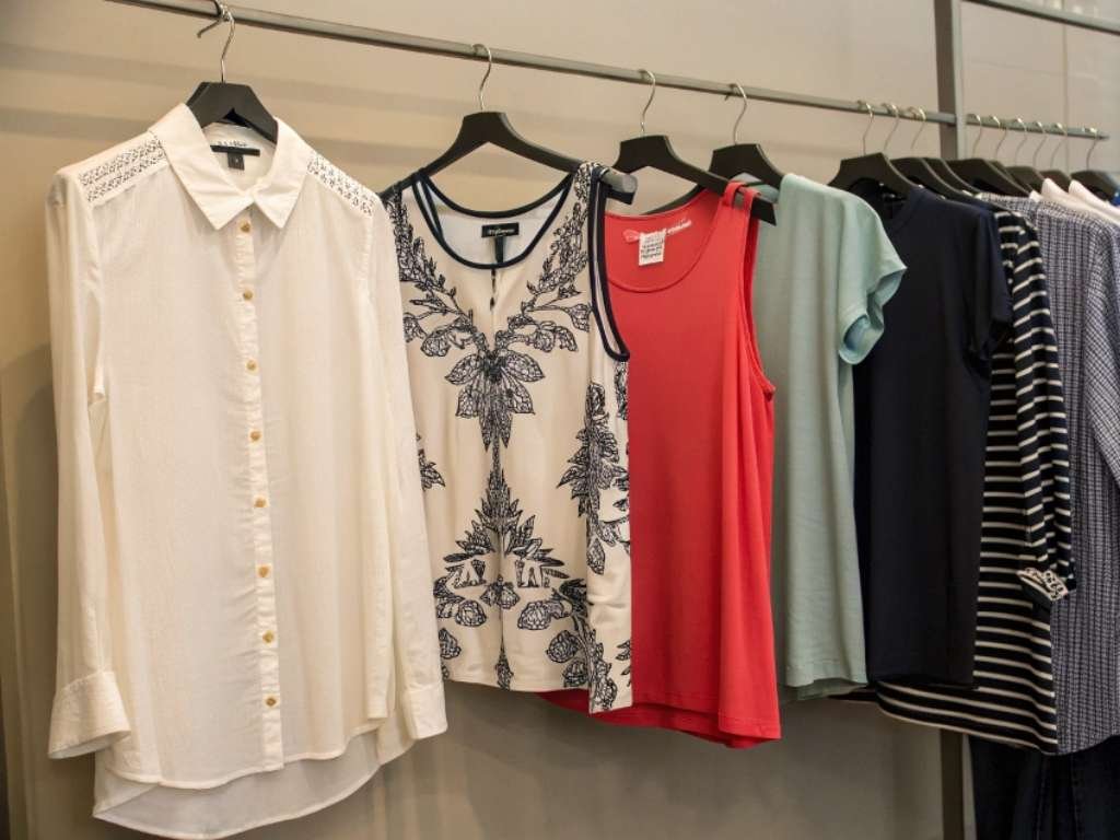Various women’s shirts and tops hanging neatly on clothing rack.