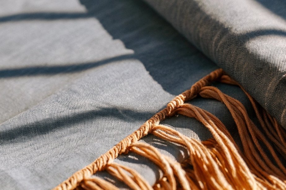 Close-up of folded grey fabric with golden fringe detail